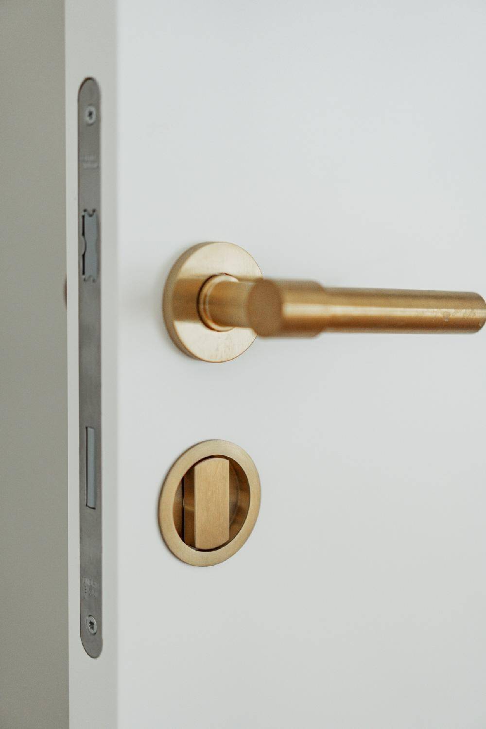Detailaufnahme einer modernen Tür mit goldfarbenem Griff und Schließmechanismus.