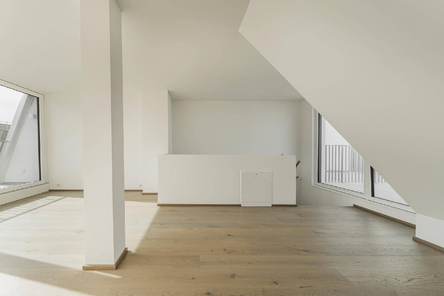Heller, offener Wohnbereich mit Holzboden und großen Fenstern, die viel Licht hereinlassen.