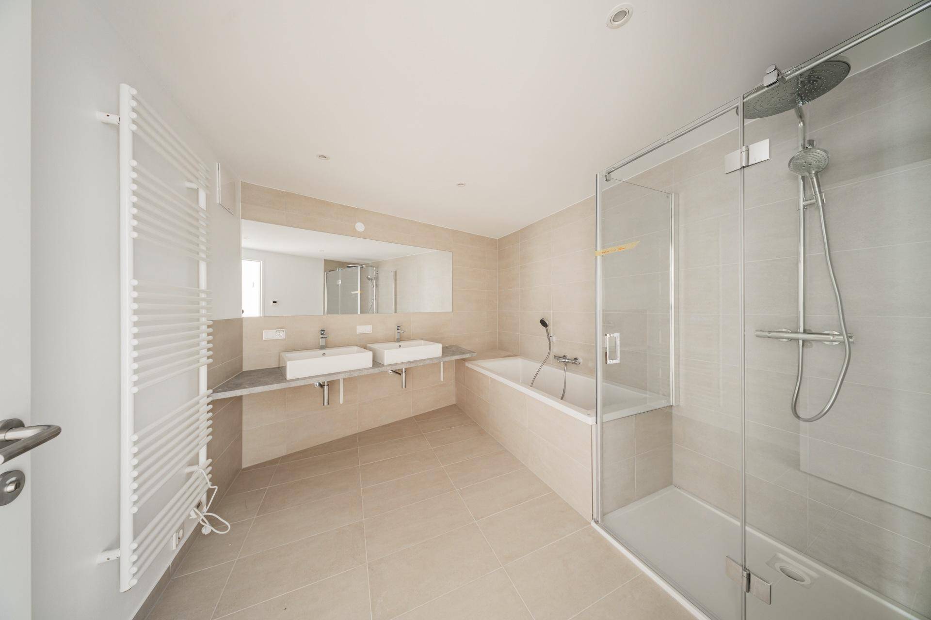 Modernes Badezimmer mit Doppelwaschbecken, Badewanne und separater Glasdusche.