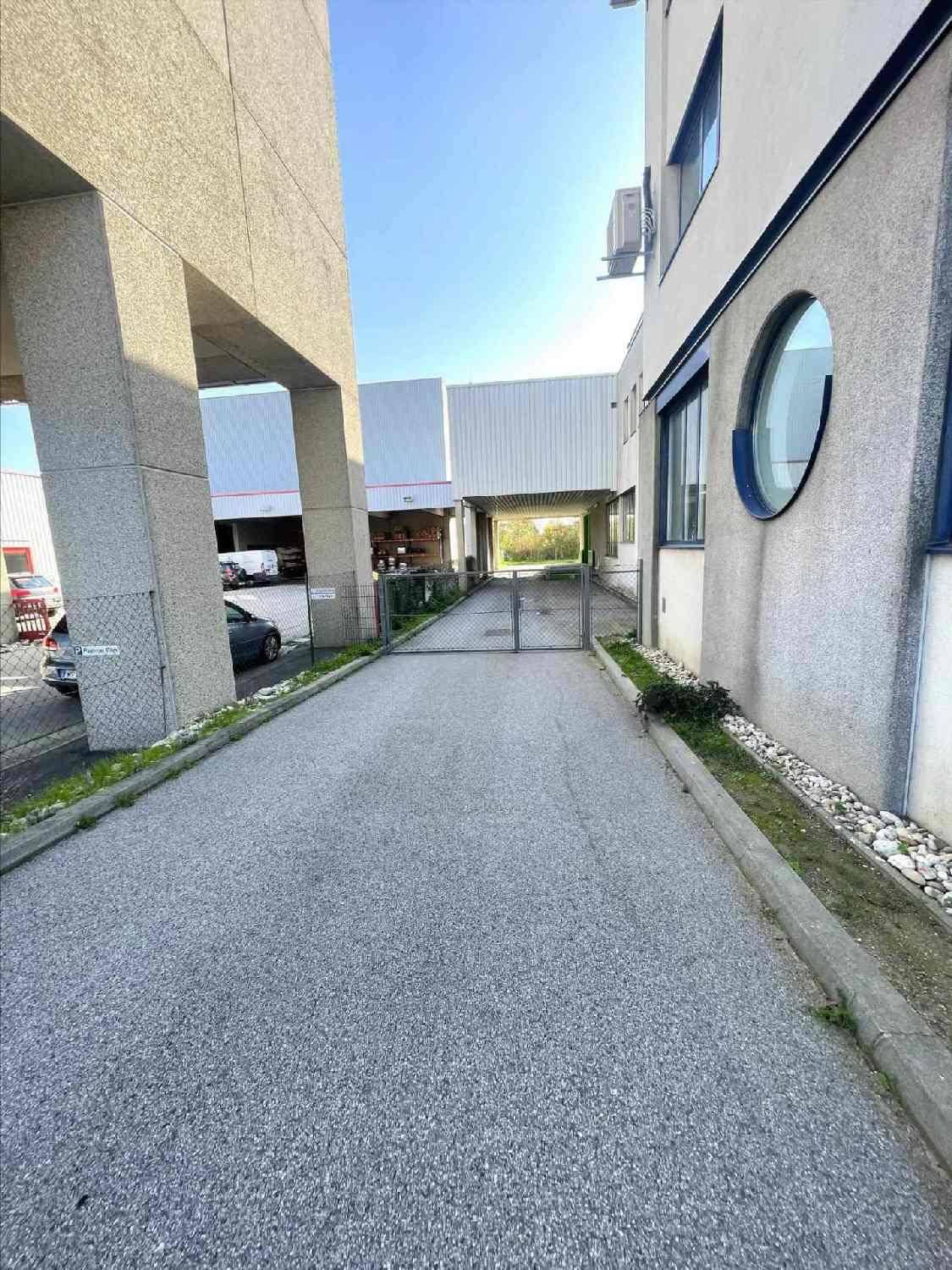 Außenansicht eines Gewerbegebäudes mit Zufahrt zwischen zwei Gebäudeteilen und einem Tor.