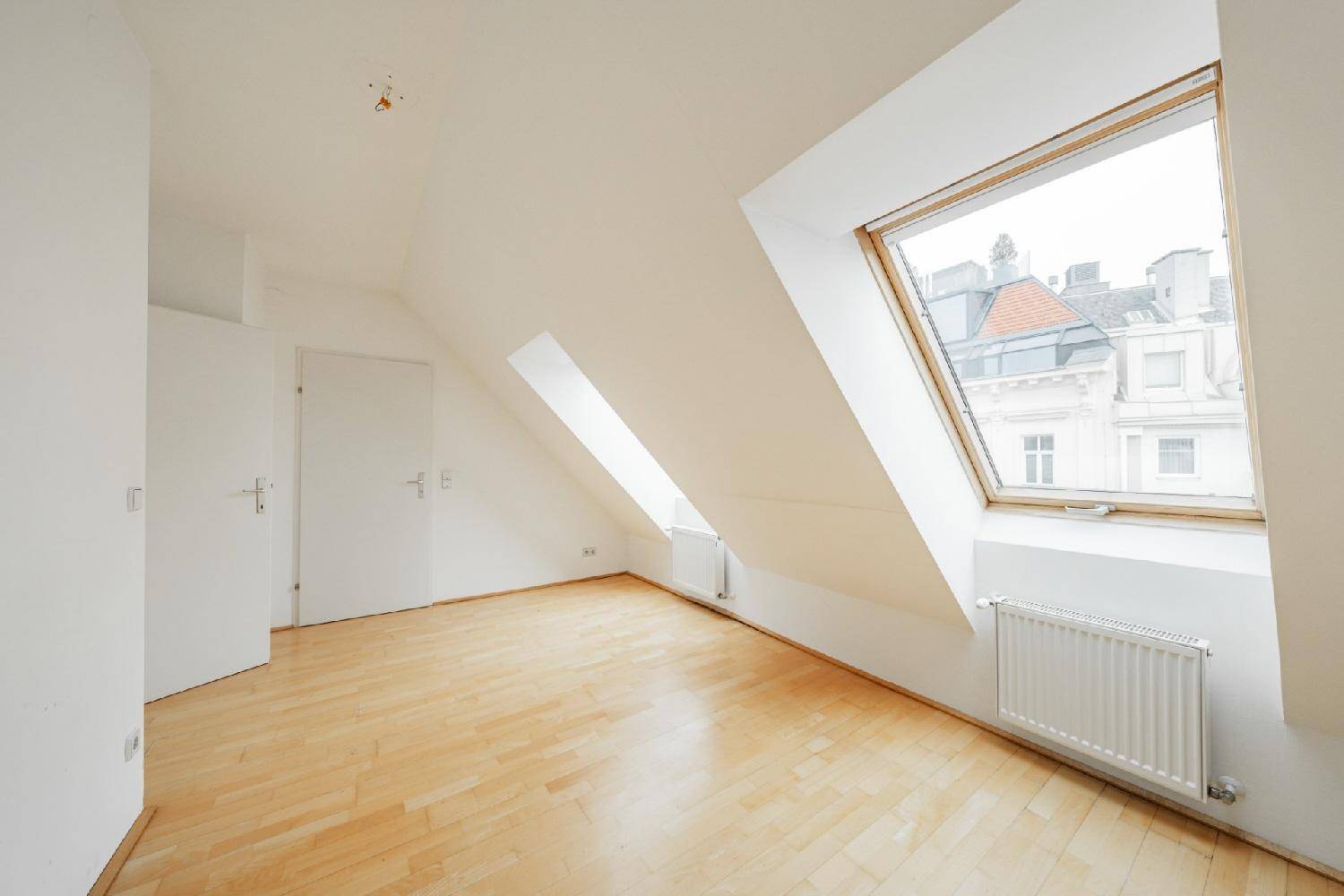 Geräumiges Schlafzimmer mit Holzfußboden, Dachschräge und großem Dachfenster, inklusive Einbauschrank.
