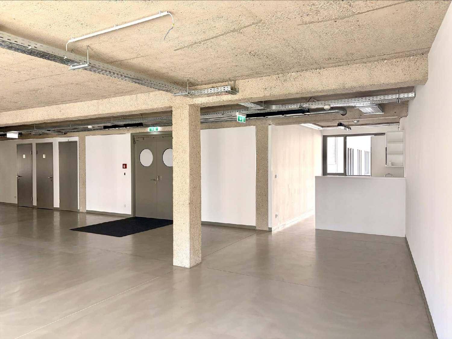 Offener Bürobereich mit Betonboden, mehreren Türen und sichtbaren Deckeninstallationen.