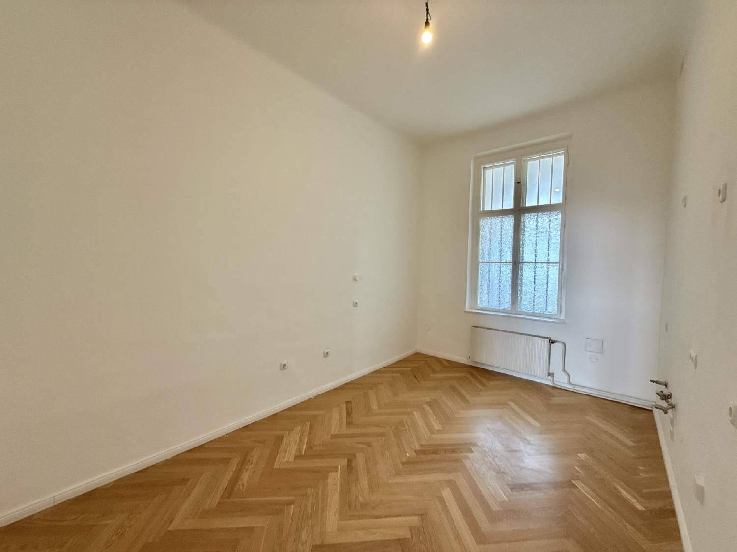 Helles Zimmer mit Fischgrätparkettboden und einem Fenster mit Milchglas, ideal als Schlaf- oder Arbeitszimmer.