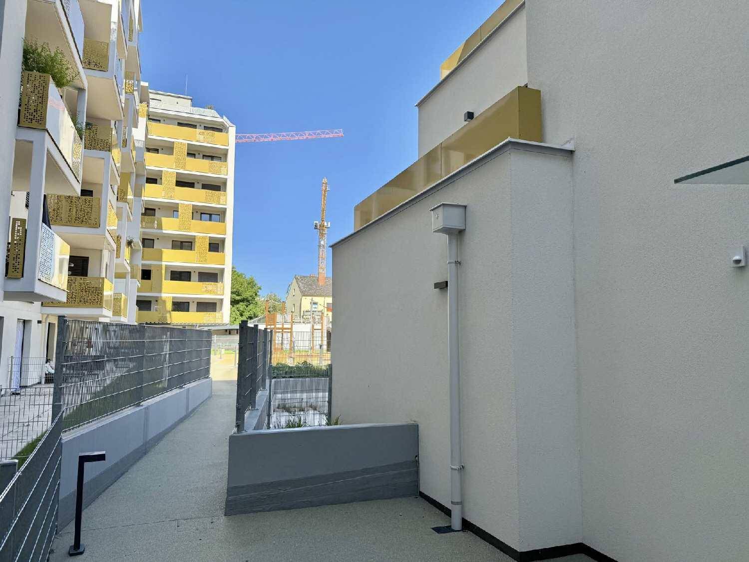 Außenansicht eines modernen Wohnkomplexes mit Zugangsweg und umliegenden Gebäuden.