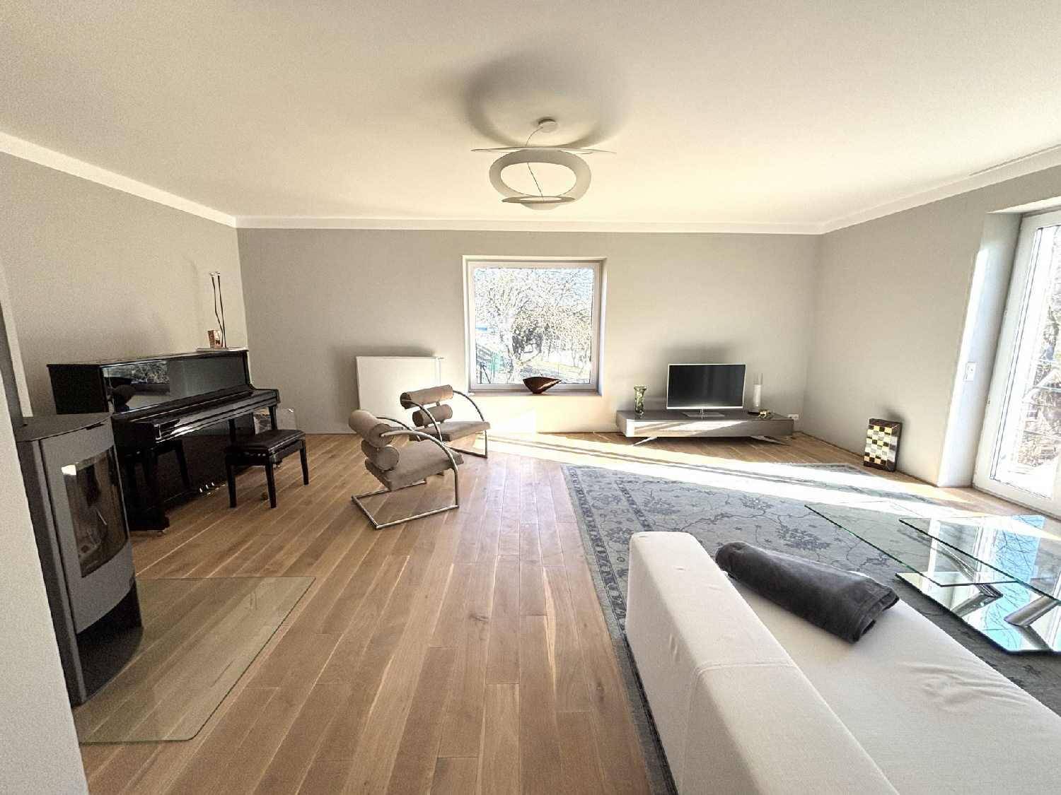 Helles Wohnzimmer mit Holzboden, Kaminofen und einem Klavier, modern eingerichtet.