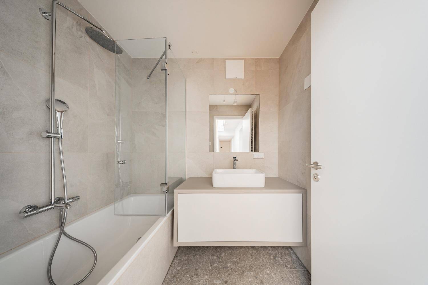 Modernes Badezimmer mit Badewanne, Dusche, Waschtisch und hellen Fliesen in zeitgemäßem Design.