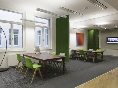 Offener Bürobereich mit mehreren Besprechungstischen, grünen Akzenten und großen Fenstern für Meetings.