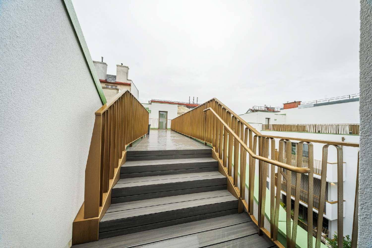 Außentreppe mit goldenen Geländern, die zu den oberen Terrassenbereichen des Gebäudes führt.