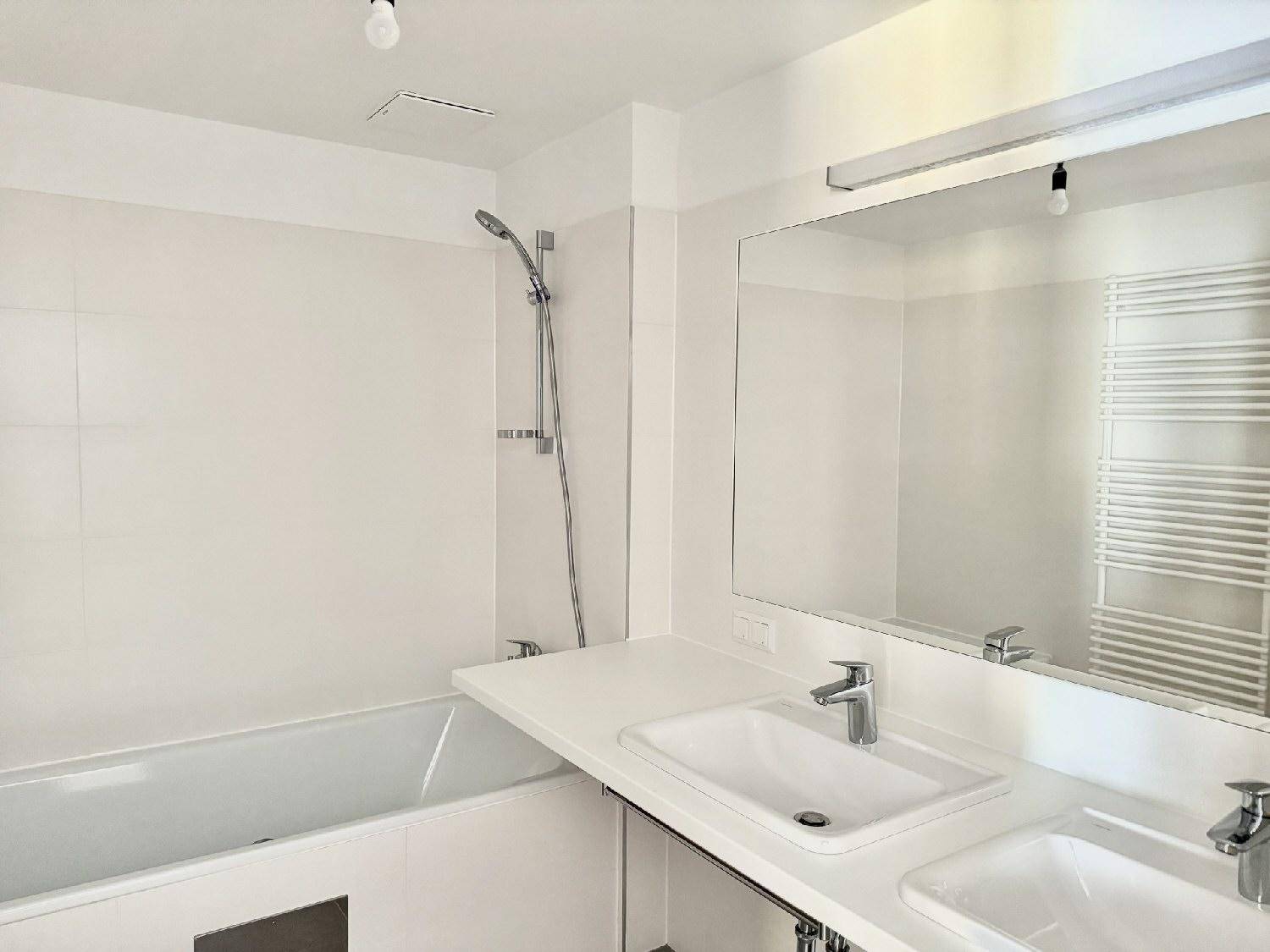 Modernes Badezimmer mit Badewanne, Doppelwaschbecken und beheiztem Handtuchhalter.
