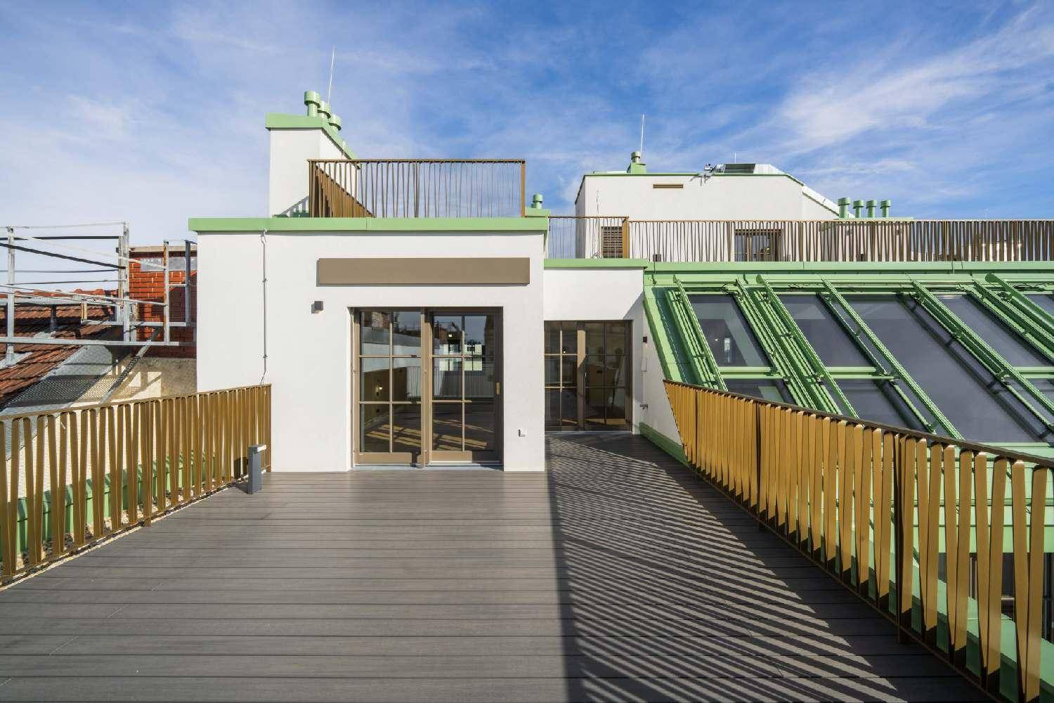 Weitläufige Dachterrasse mit Zugang zu Innenräumen und Blick auf die umliegenden Gebäude.