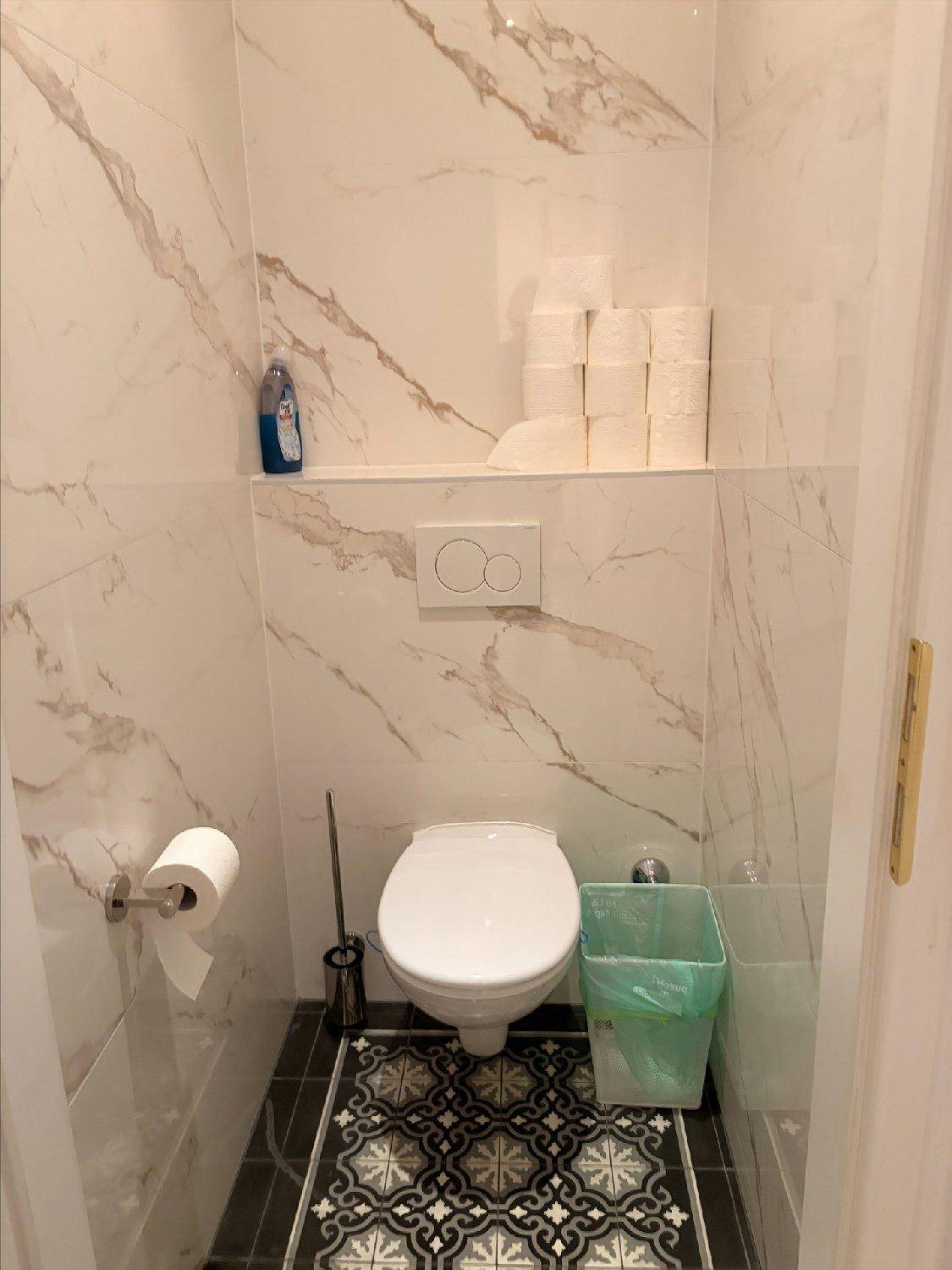Modern gefliestes Gäste-WC mit Wand-WC und stilvollen Marmor-Effekt-Fliesen an den Wänden.