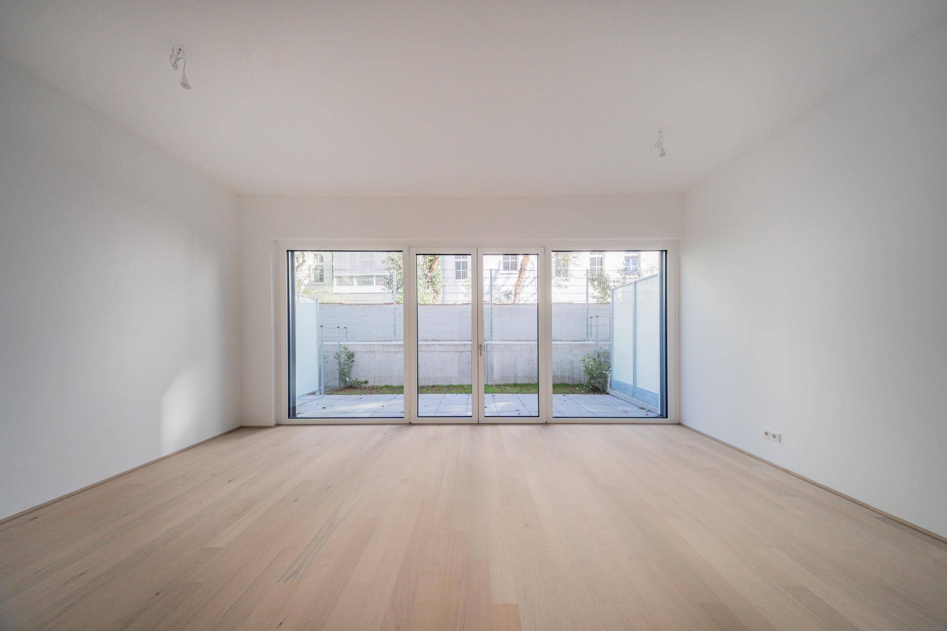 Großer, heller Wohnbereich mit Holzboden und breiter Fensterfront zum Garten.