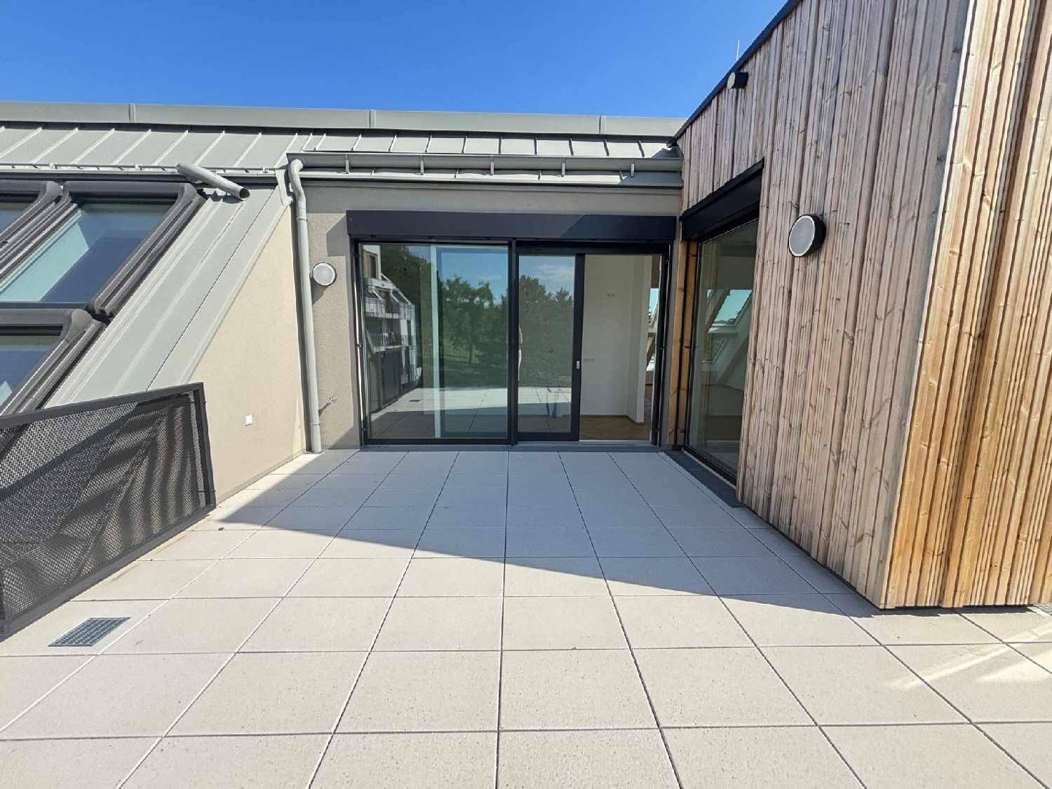 Helle Dachterrasse mit modernen Fliesen und Holzverkleidung, direktem Zugang zu den Innenräumen.