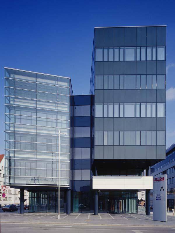 Auffälliges Bürogebäude mit einer markanten Glasfront und dunklen, überhängenden Gebäudeteilen.
