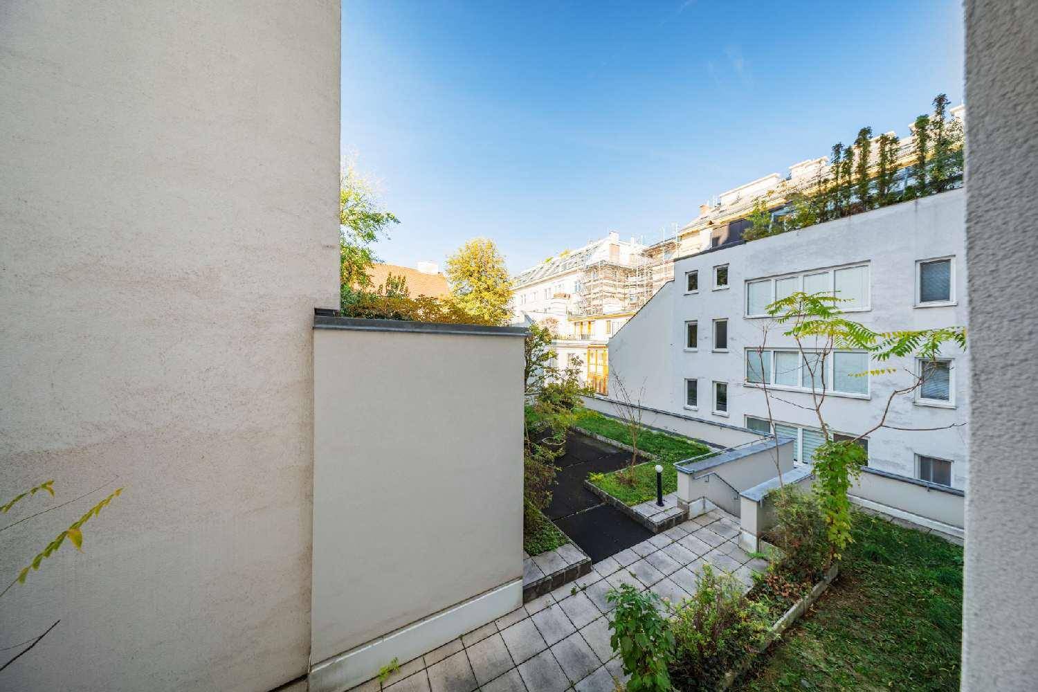 Blick auf einen begrünten Innenhof mit gepflasterten Wegen und modernen Gebäudefassaden.