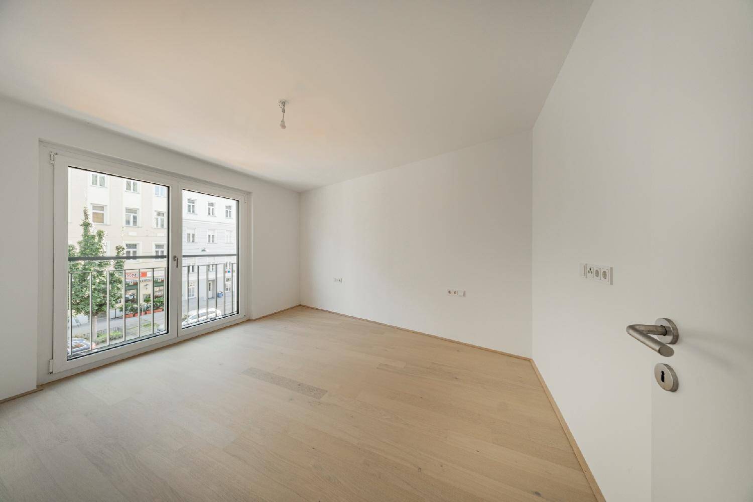 Helles Zimmer mit Parkettboden und französischem Balkon, ideal als Schlaf- oder Arbeitszimmer.
