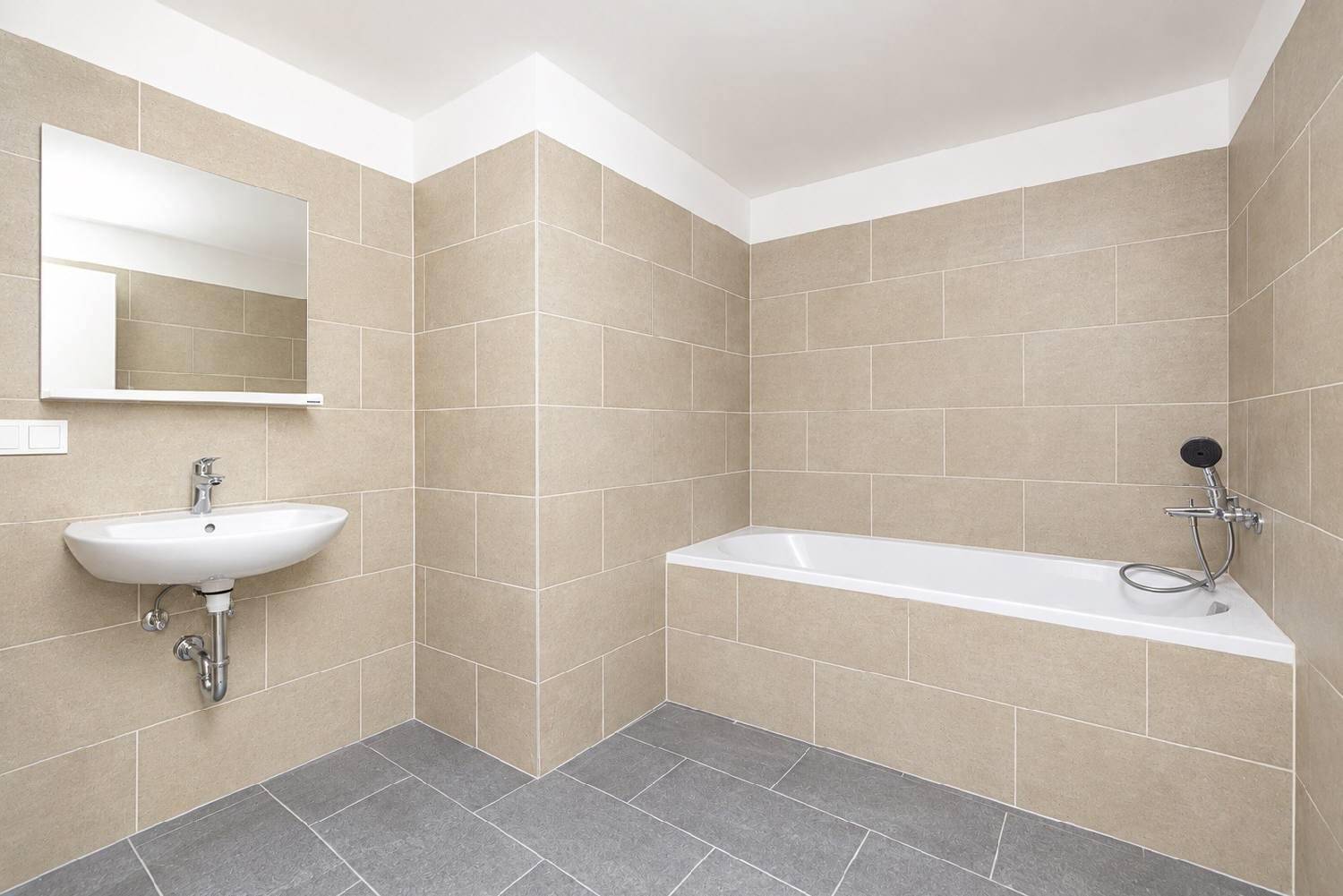 Modernes Badezimmer mit beigefarbenen Wandfliesen, Badewanne und einem einzelnen Waschbecken.