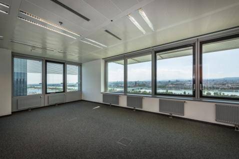 Geräumiges Büro mit großen Fenstern, Teppichboden und weitem Blick auf die Stadt und den Fluss.