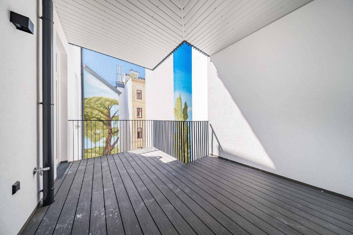 Geräumiger Balkon mit Holzdielenboden und Blick auf die umliegenden Gebäude.