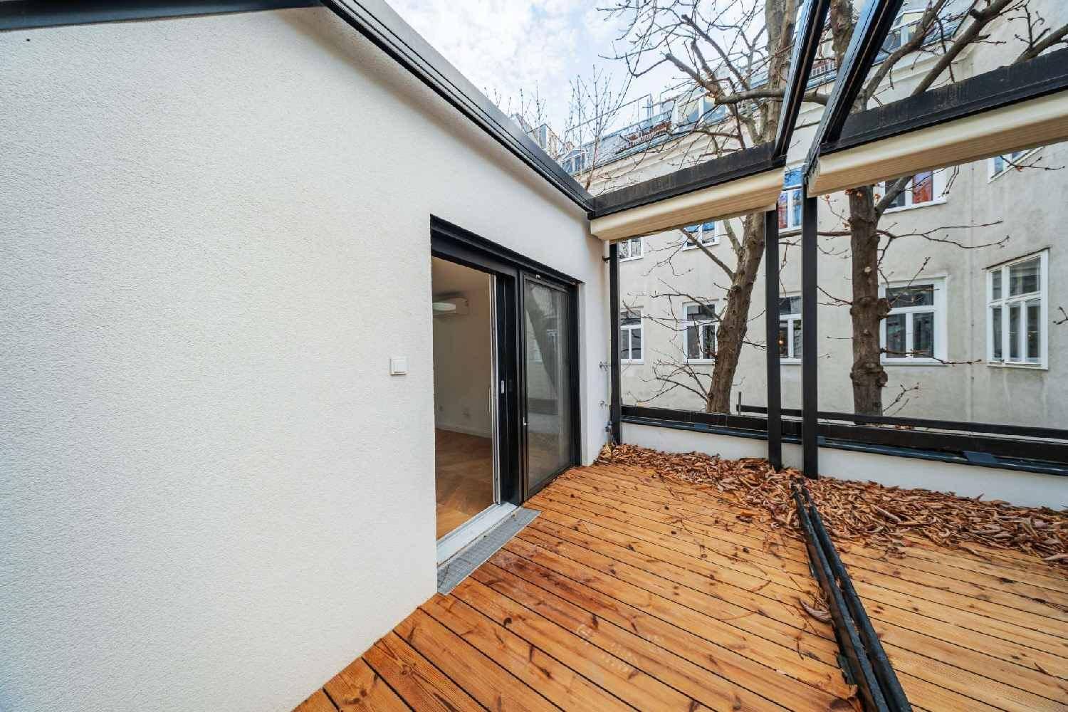 Holzterrasse mit Schiebetür zum Innenbereich und Blick auf die umliegenden Gebäude.