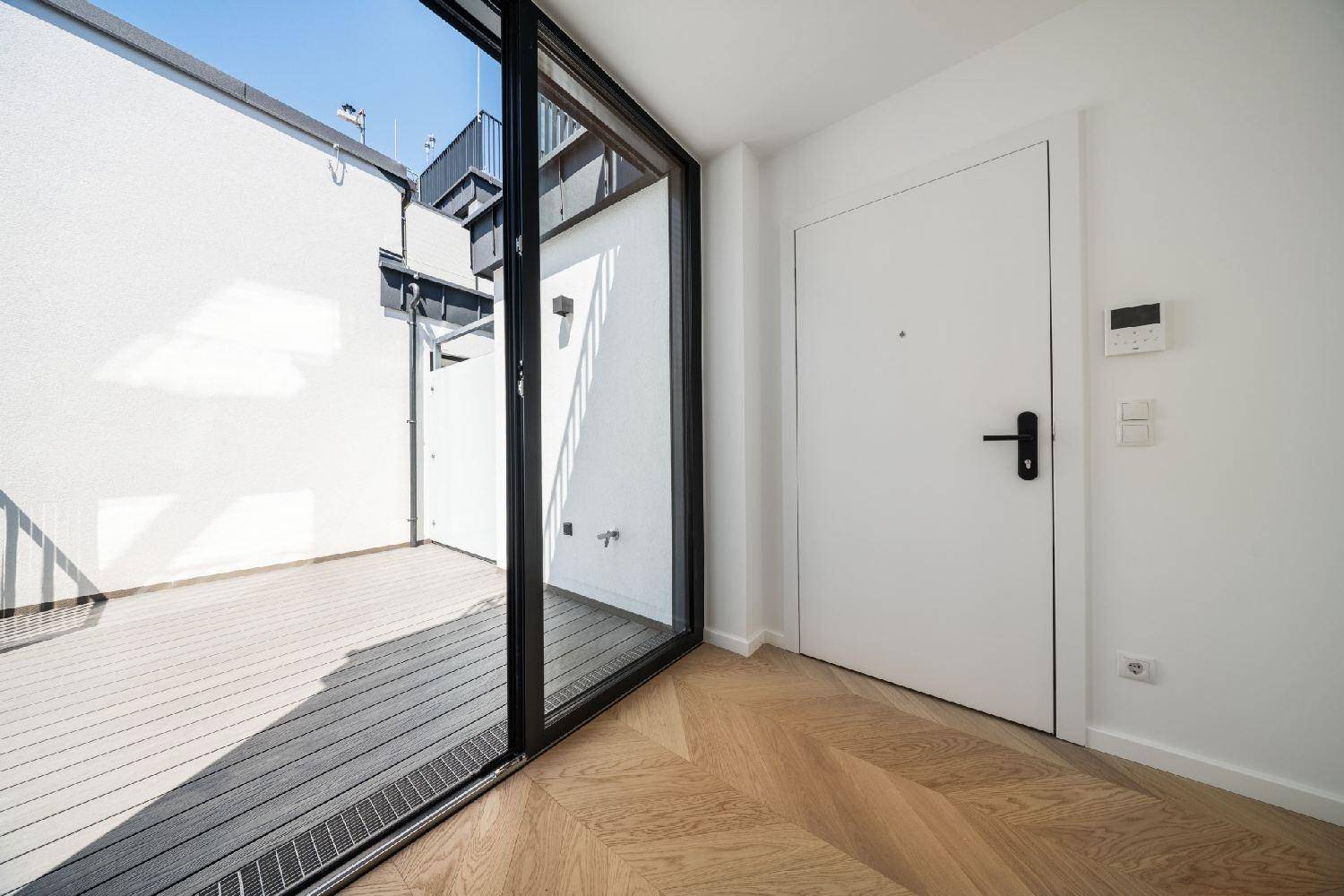 Innenansicht mit breiter Glasschiebetür, die zu einer modernen Außenterrasse führt.