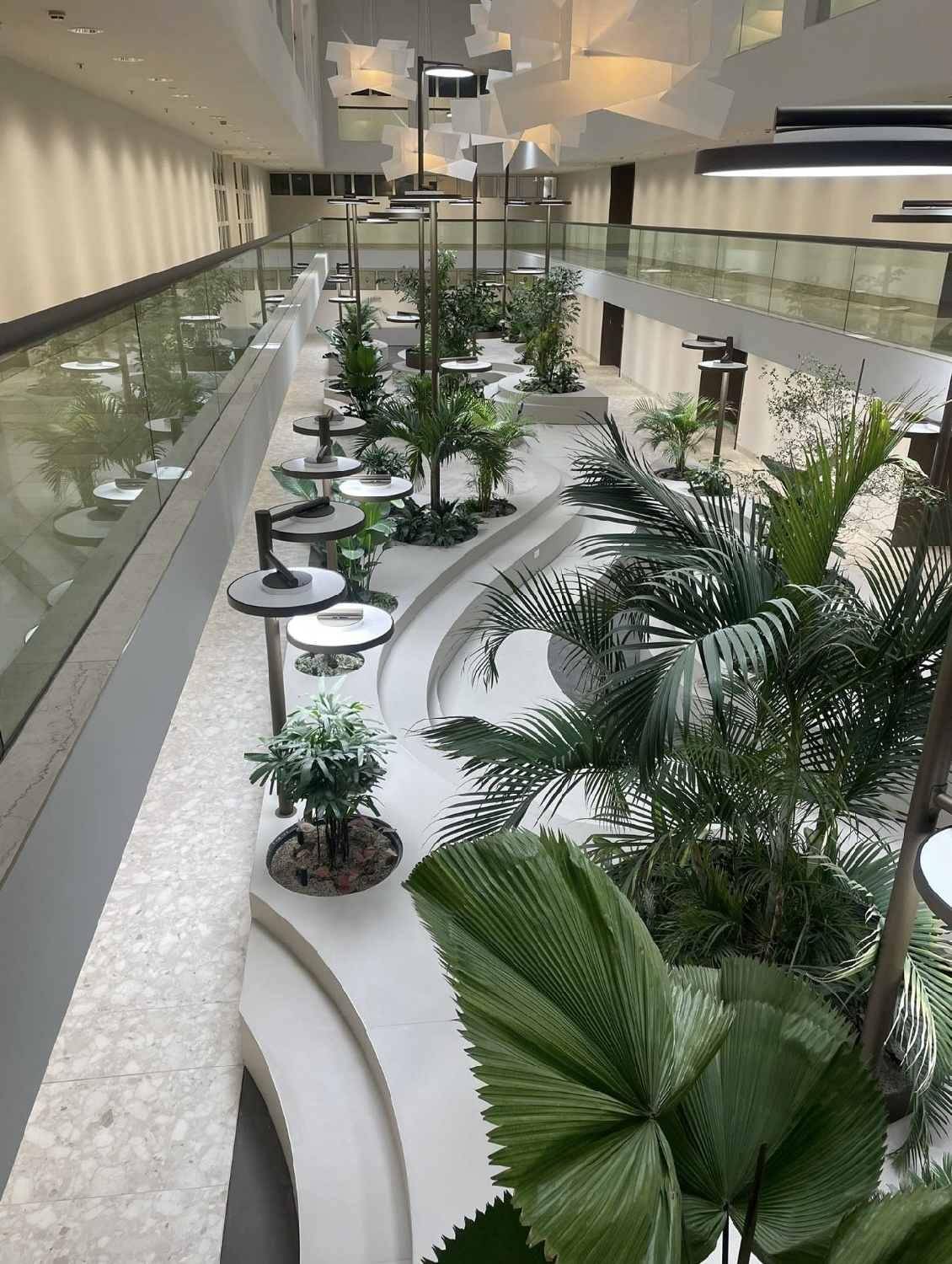 Modernes Atrium mit üppiger Bepflanzung, mehreren Ebenen und stilvoller Beleuchtung.