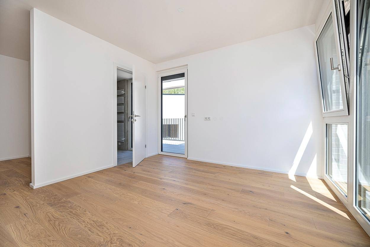 Modernes Schlafzimmer mit Parkettboden und Zugang zu einem angrenzenden Badezimmer.