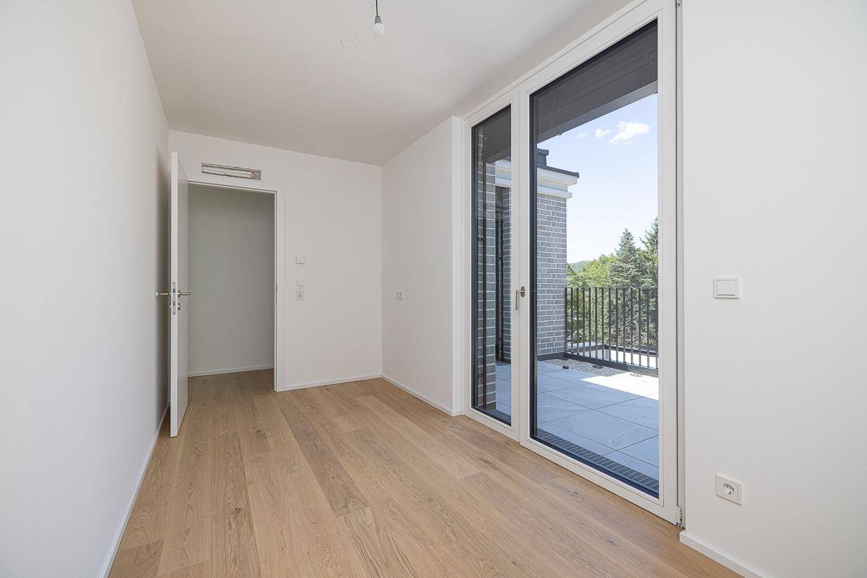 Helles Schlafzimmer mit Holzboden und direktem Zugang zu einer privaten Terrasse.
