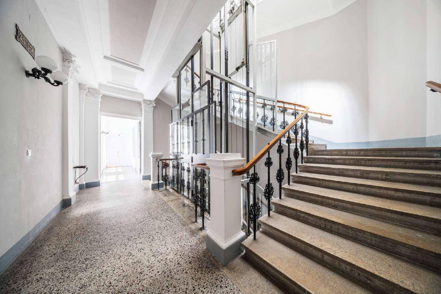 Historisches Treppenhaus mit Terrazzoboden, schmiedeeisernem Geländer und modernem Glasaufzug.