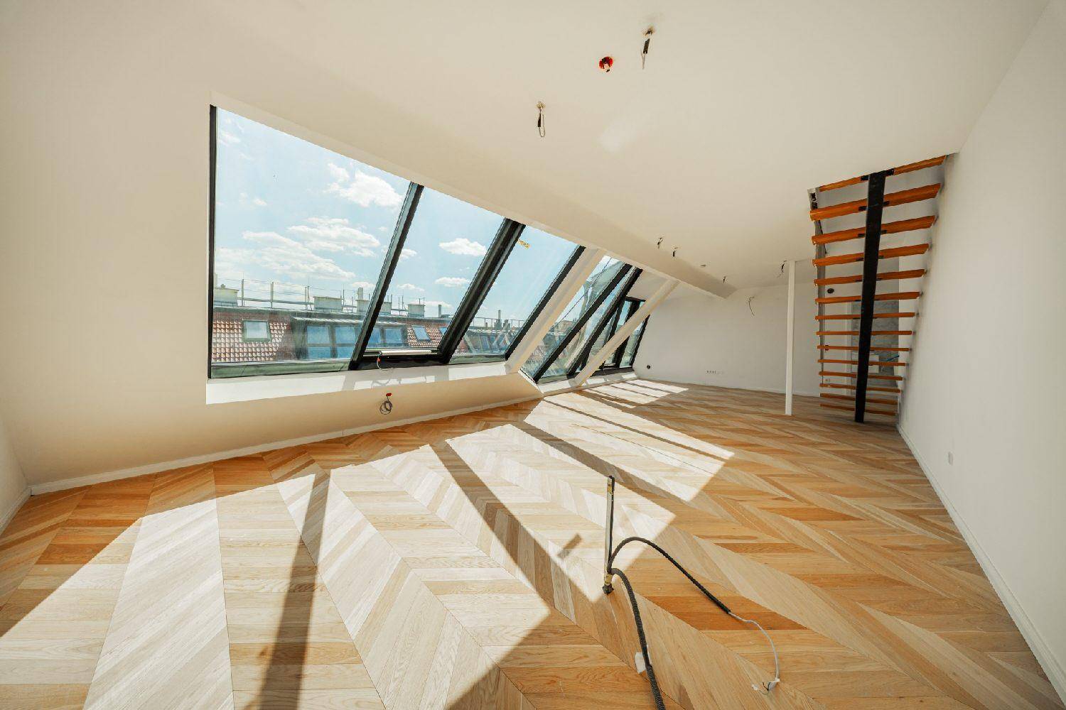 Lichtdurchfluteter Raum mit schrägem Dachfenster und Fischgrätparkett, ideal für ein modernes Wohnkonzept.