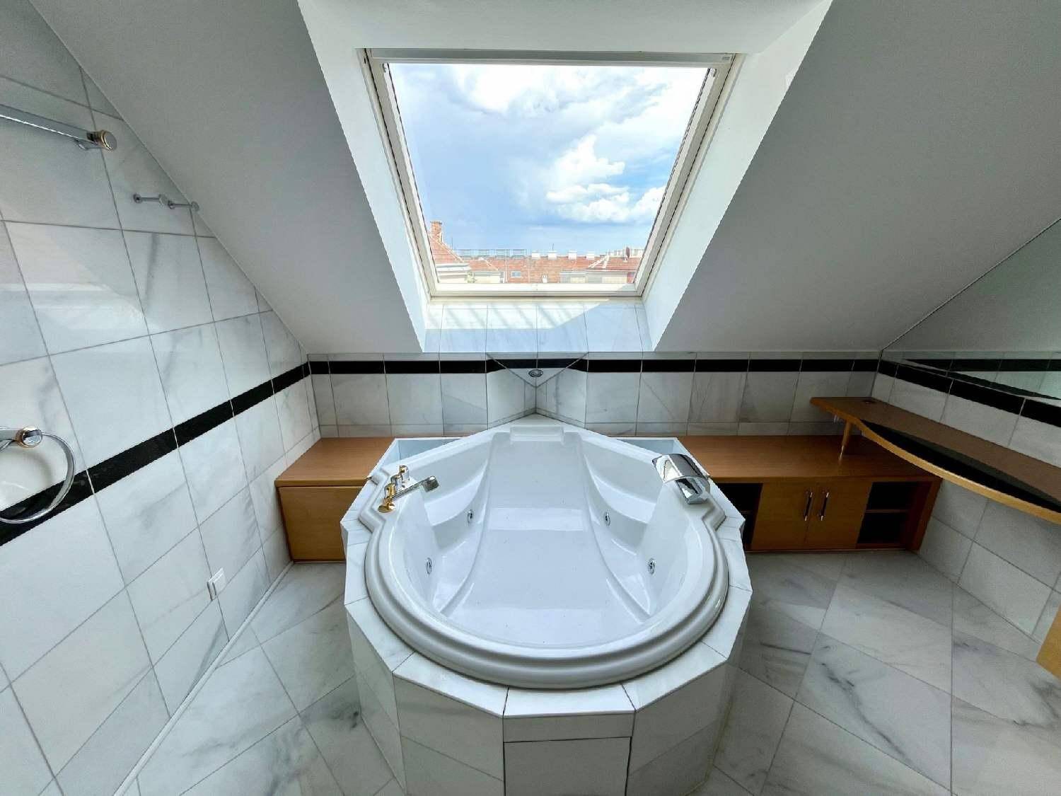 Modernes Badezimmer mit Whirlpool-Badewanne, Marmorfliesen und großem Dachfenster für viel Licht.
