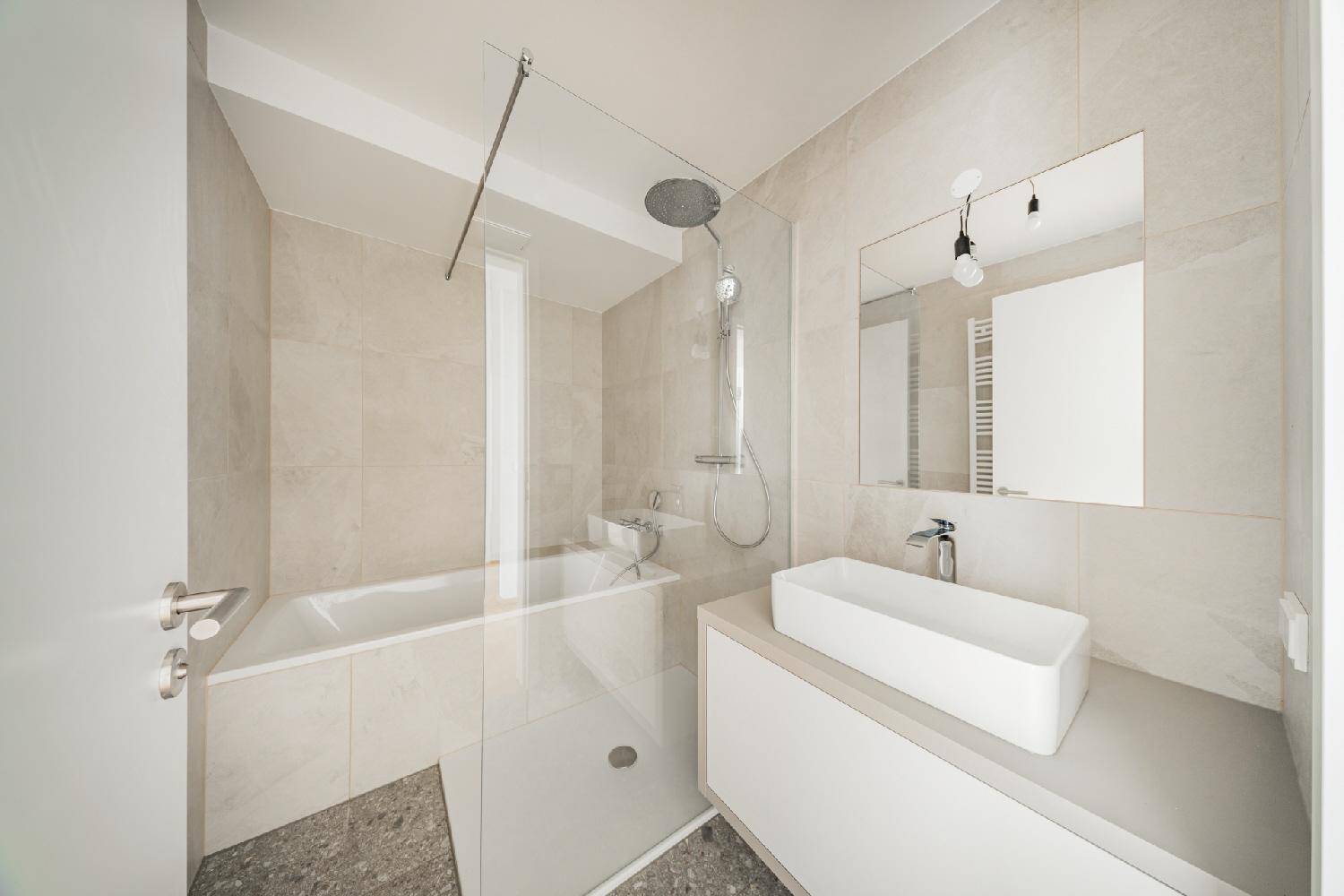 Elegantes Badezimmer mit Badewanne, modernem Waschtisch und großem Spiegel.