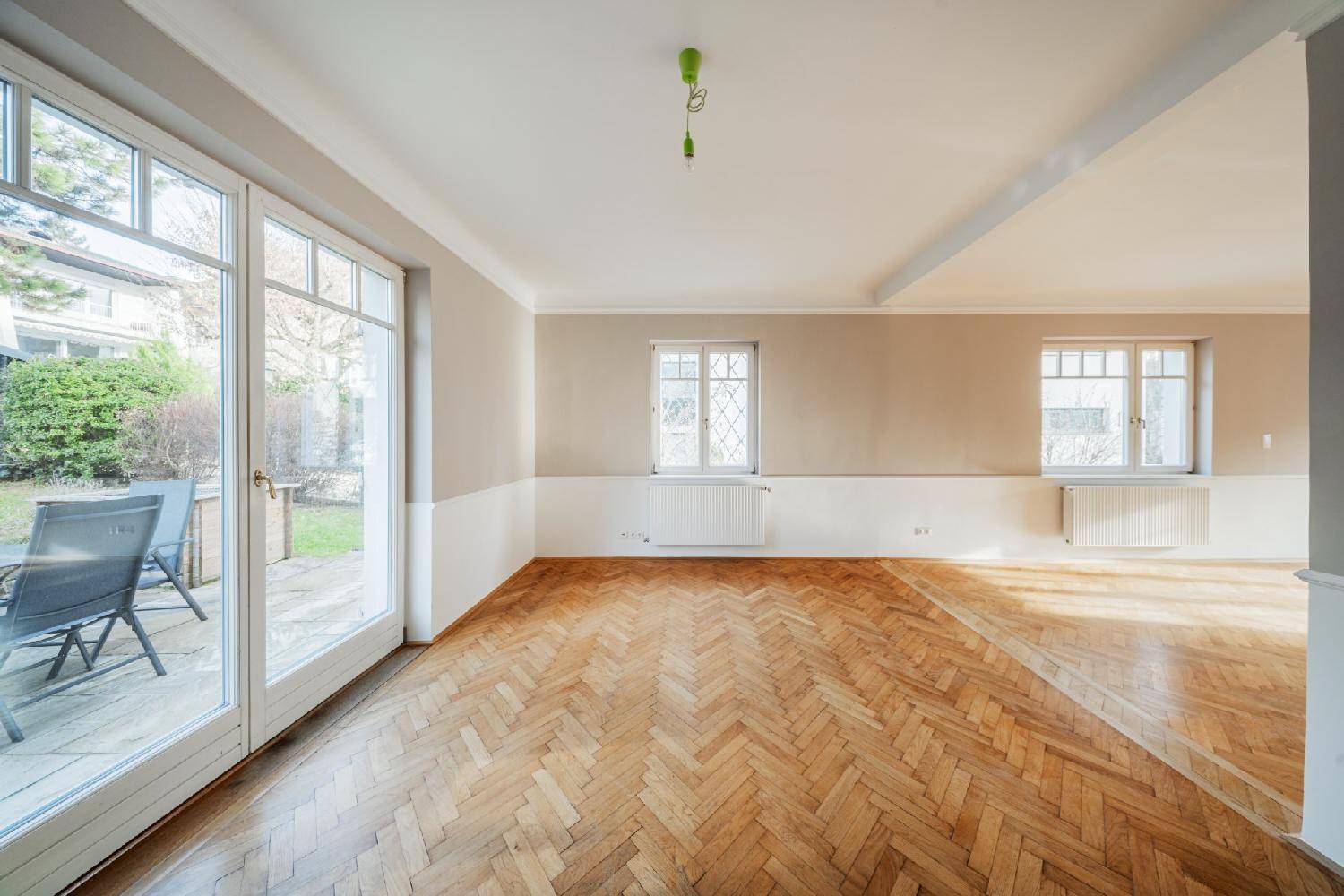 Helles Wohnzimmer mit Fischgrätparkett und direktem Zugang zur Terrasse und zum Gartenbereich.