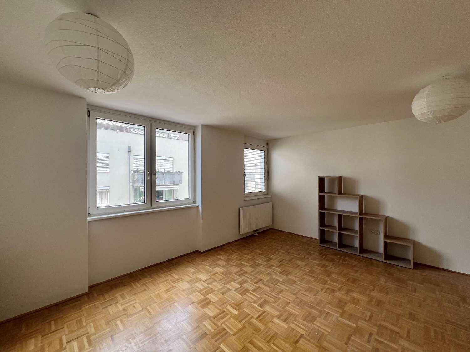 Heller Wohnraum mit Parkettboden, großen Fenstern und einem Heizkörper unter dem Fenster.