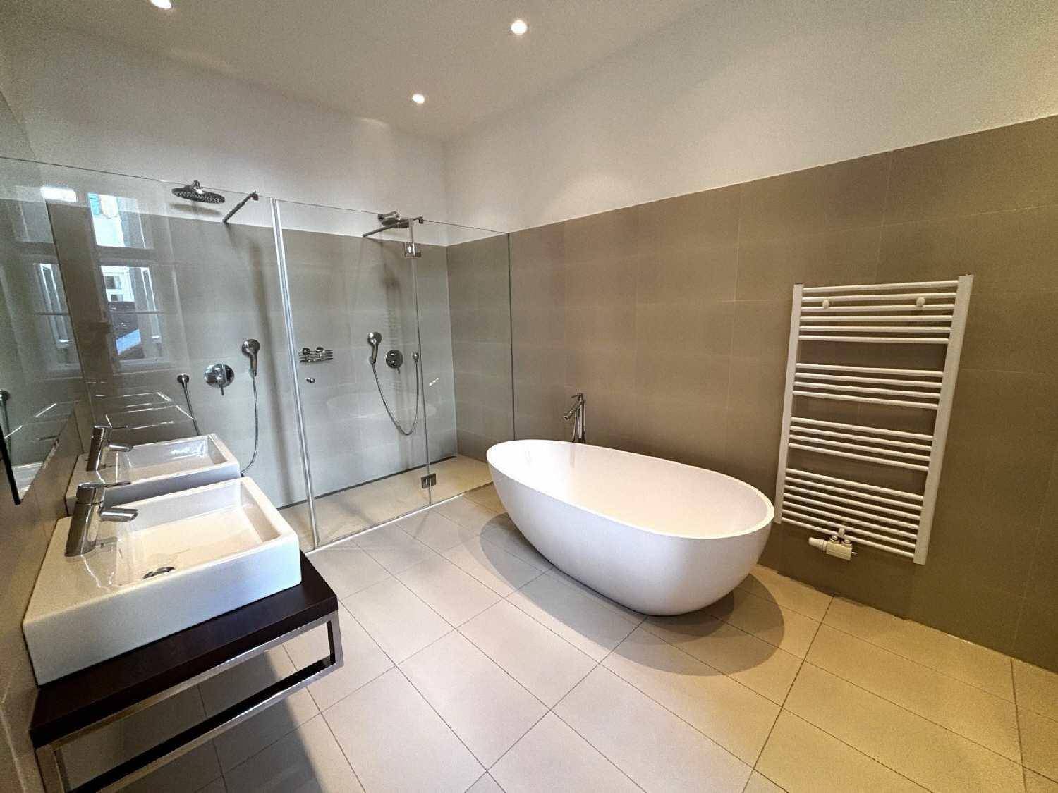 Geräumiges Badezimmer mit freistehender Wanne, großer Dusche und praktischem Handtuchheizkörper.