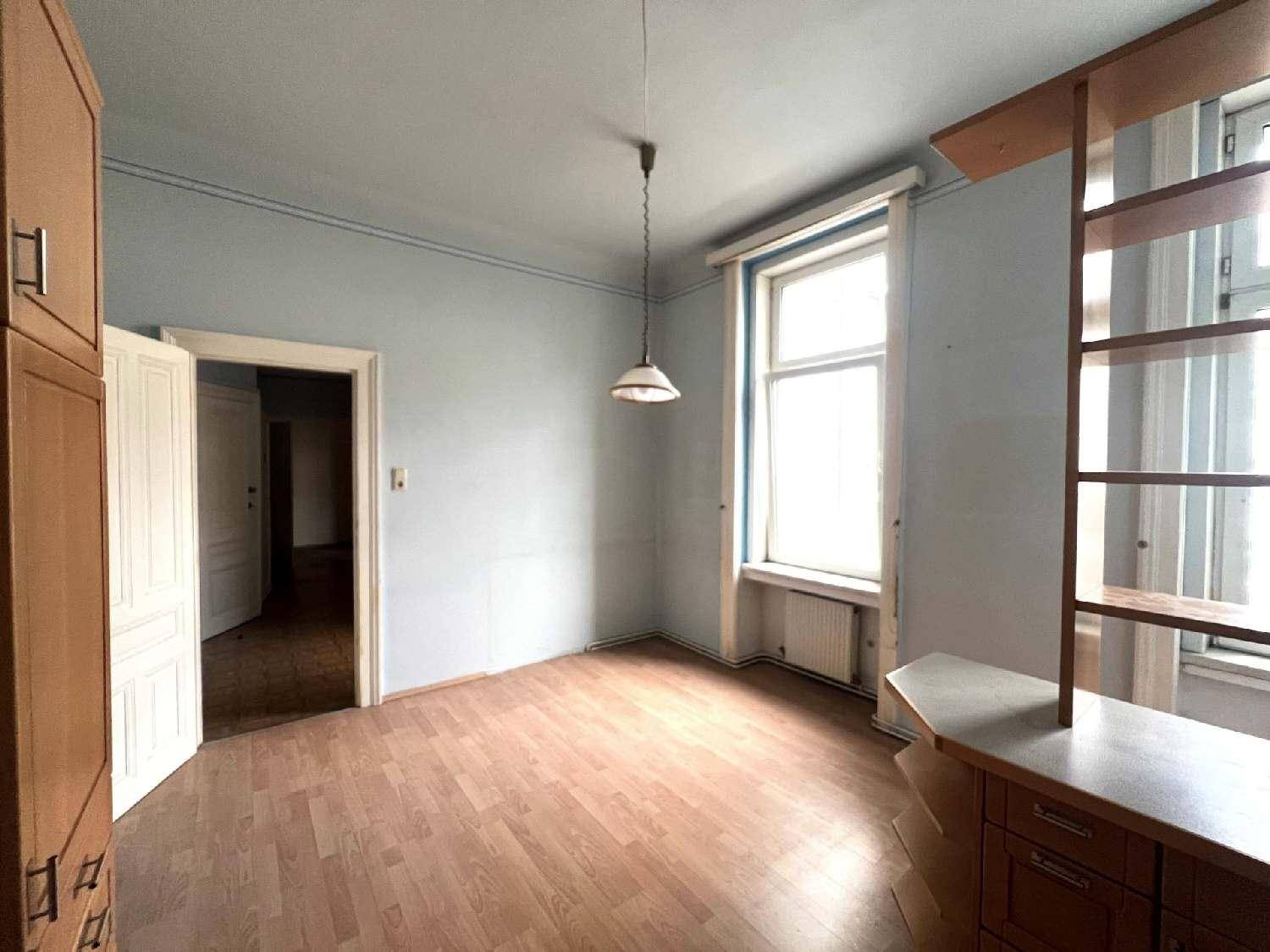 Heller Raum mit Laminatboden, blauen Wänden und großen Fenstern, angrenzend an die Küche.