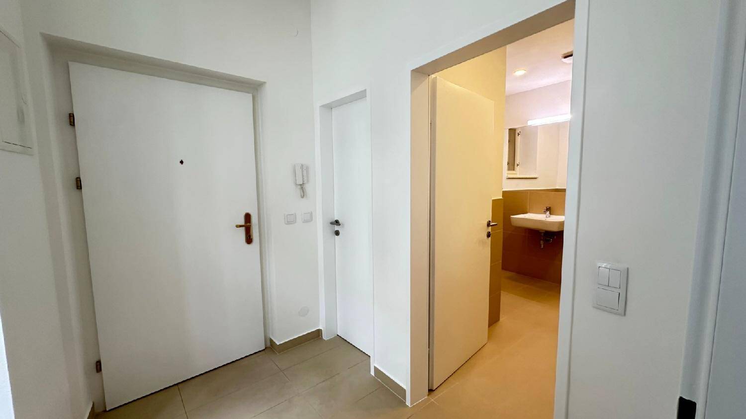 Eingangsbereich mit Fliesenboden und Zugang zum Badezimmer, helle und funktionale Gestaltung der Diele.