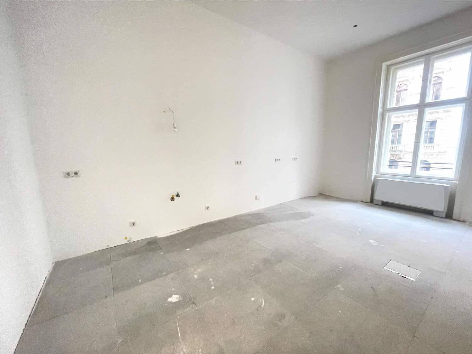 Kleiner, heller Büroraum mit einem Fenster und Betonboden, bereit für die individuelle Nutzung.
