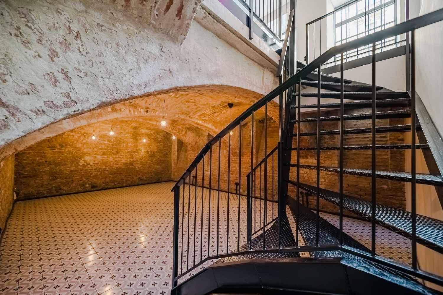 Detailansicht einer schwarzen Wendeltreppe, die in einen historischen Gewölbekeller führt.