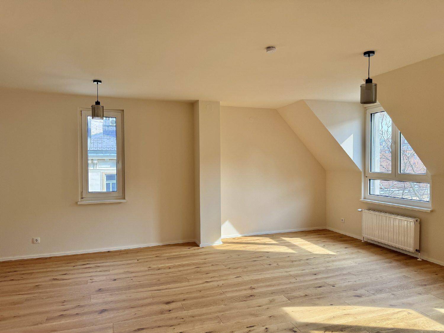 Geräumiger Wohnraum mit viel Tageslicht, Holzboden und Dachfenstern.