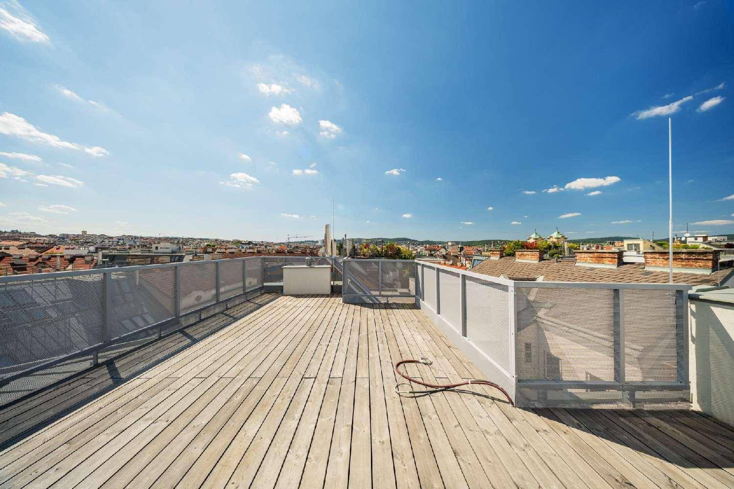 Weitläufige Dachterrasse mit Holzboden und Panoramablick über die Stadt.