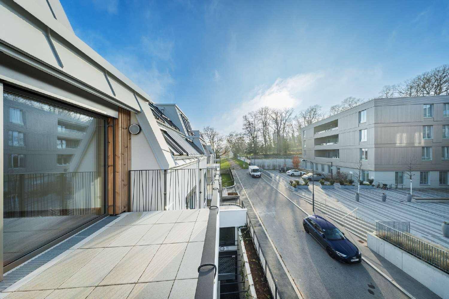 Balkon mit Weitblick auf die Straße, umliegende Gebäude und grüne Bäume.