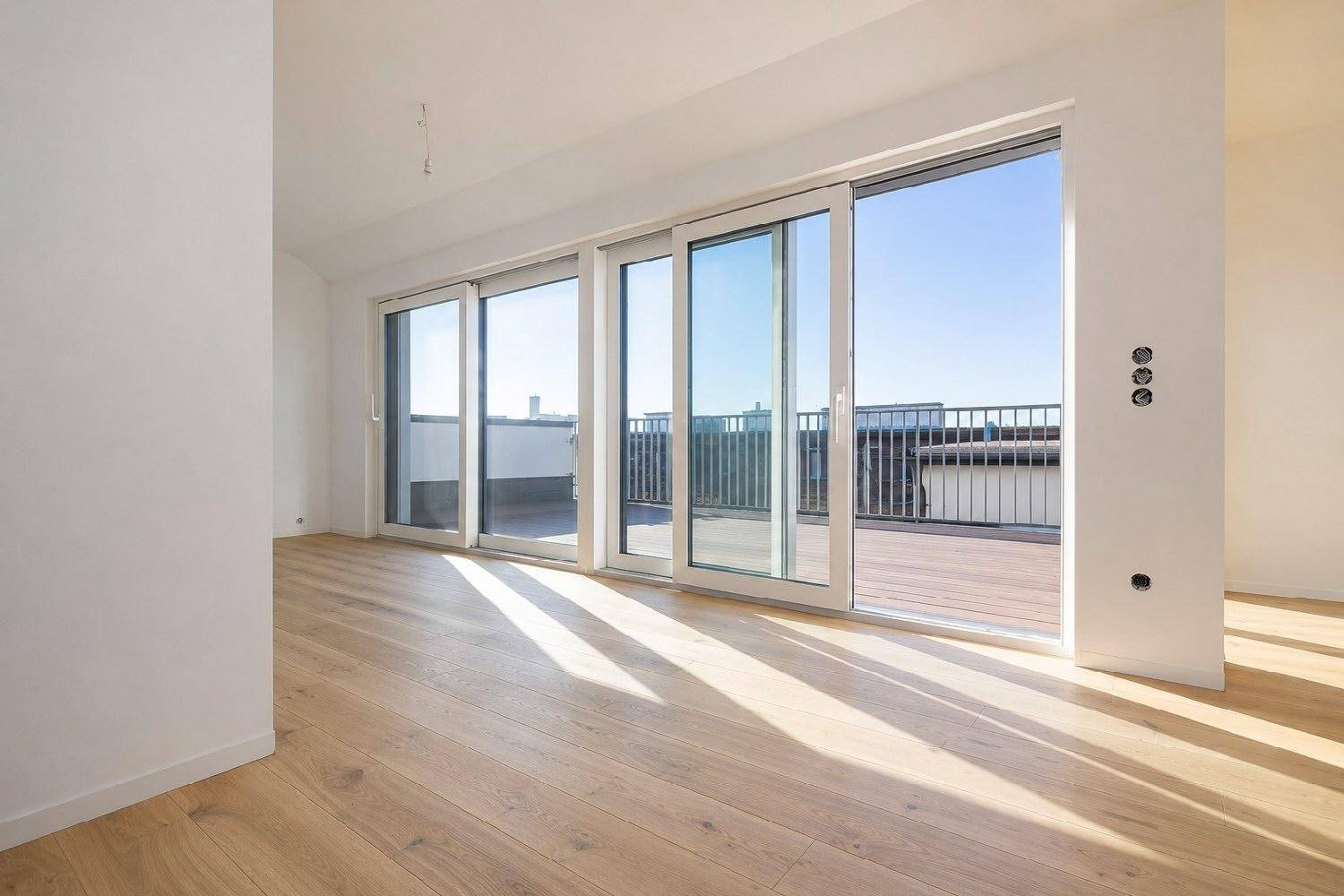 Heller Wohnraum mit Eichenparkett und großen Schiebetüren zur Dachterrasse.