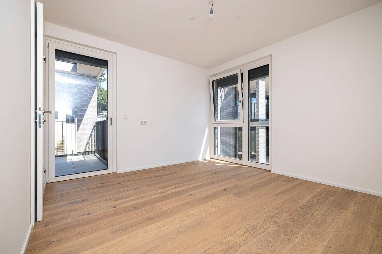 Geräumiges Schlafzimmer mit Holzboden und mehreren Fenstern für optimale Belichtung.