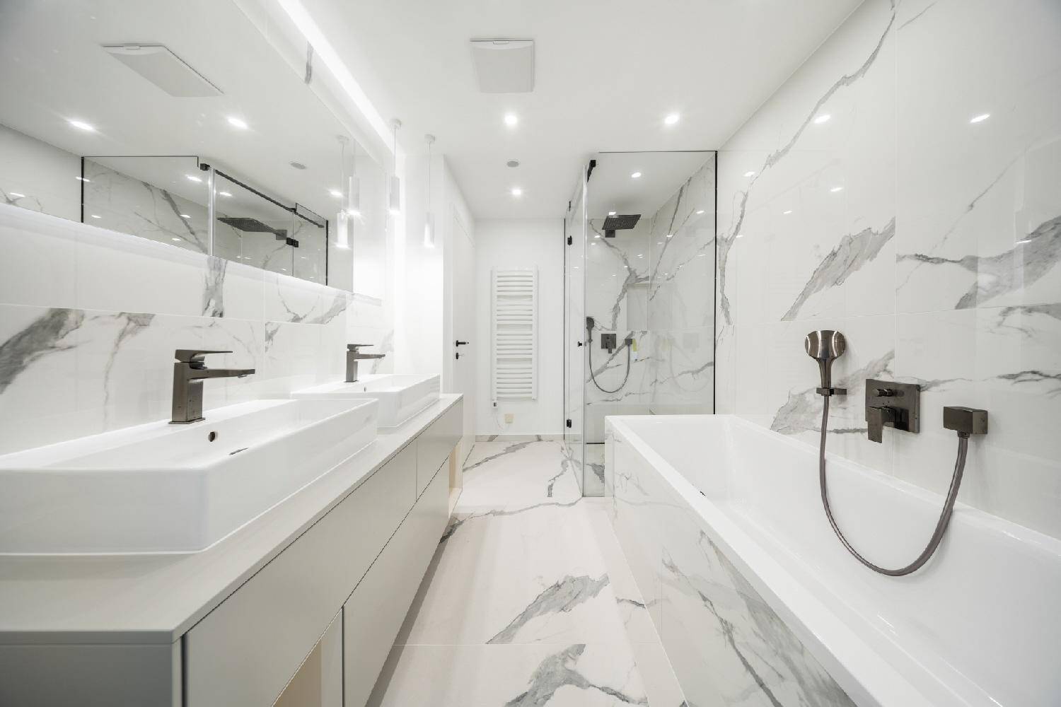Elegantes Badezimmer mit Marmoroptik-Fliesen, zwei Waschbecken, großer Dusche und Badewanne.