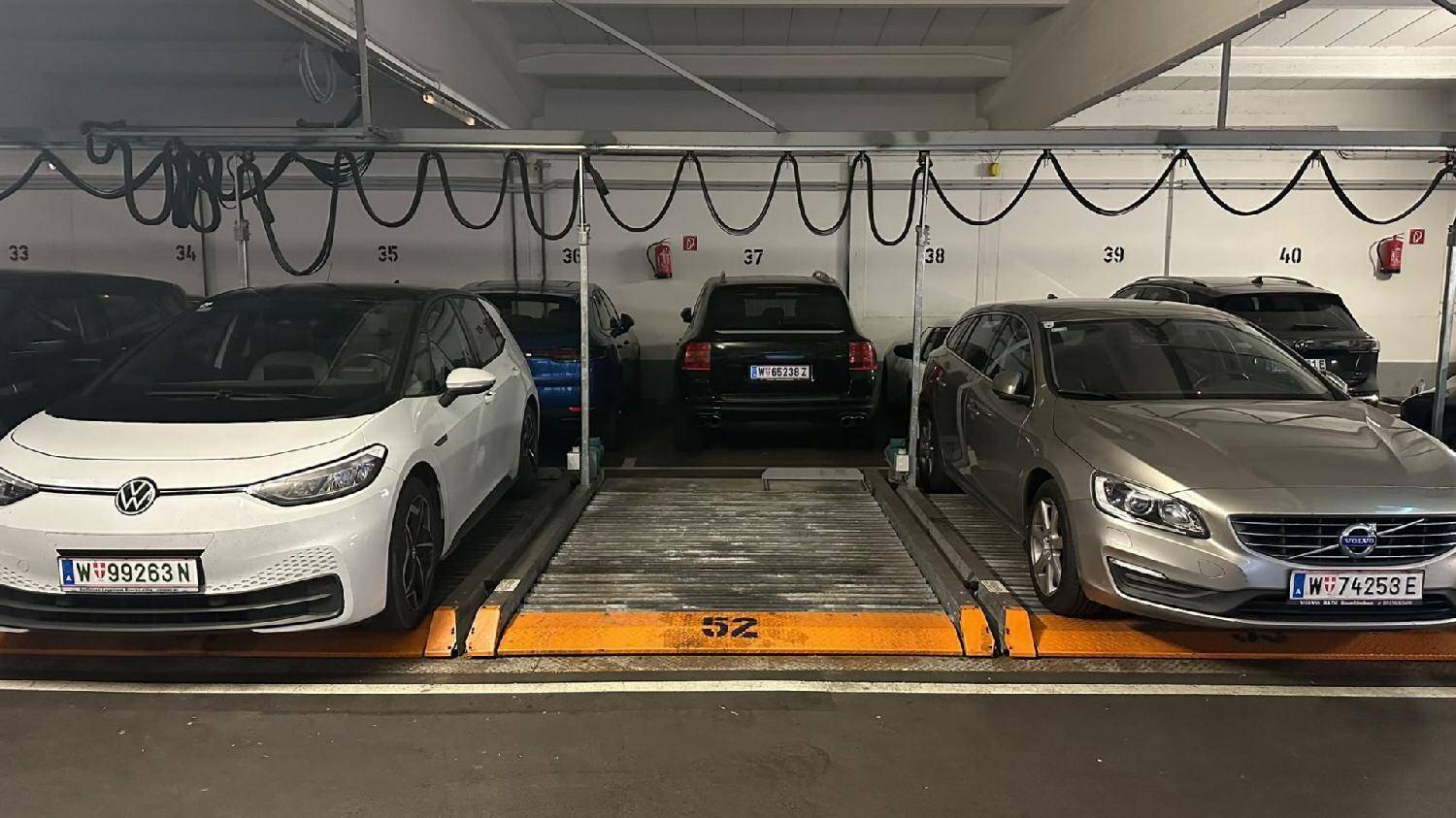 Tiefgarage mit mehreren Fahrzeugen auf den mechanischen Parkplätzen und Nummernmarkierungen.