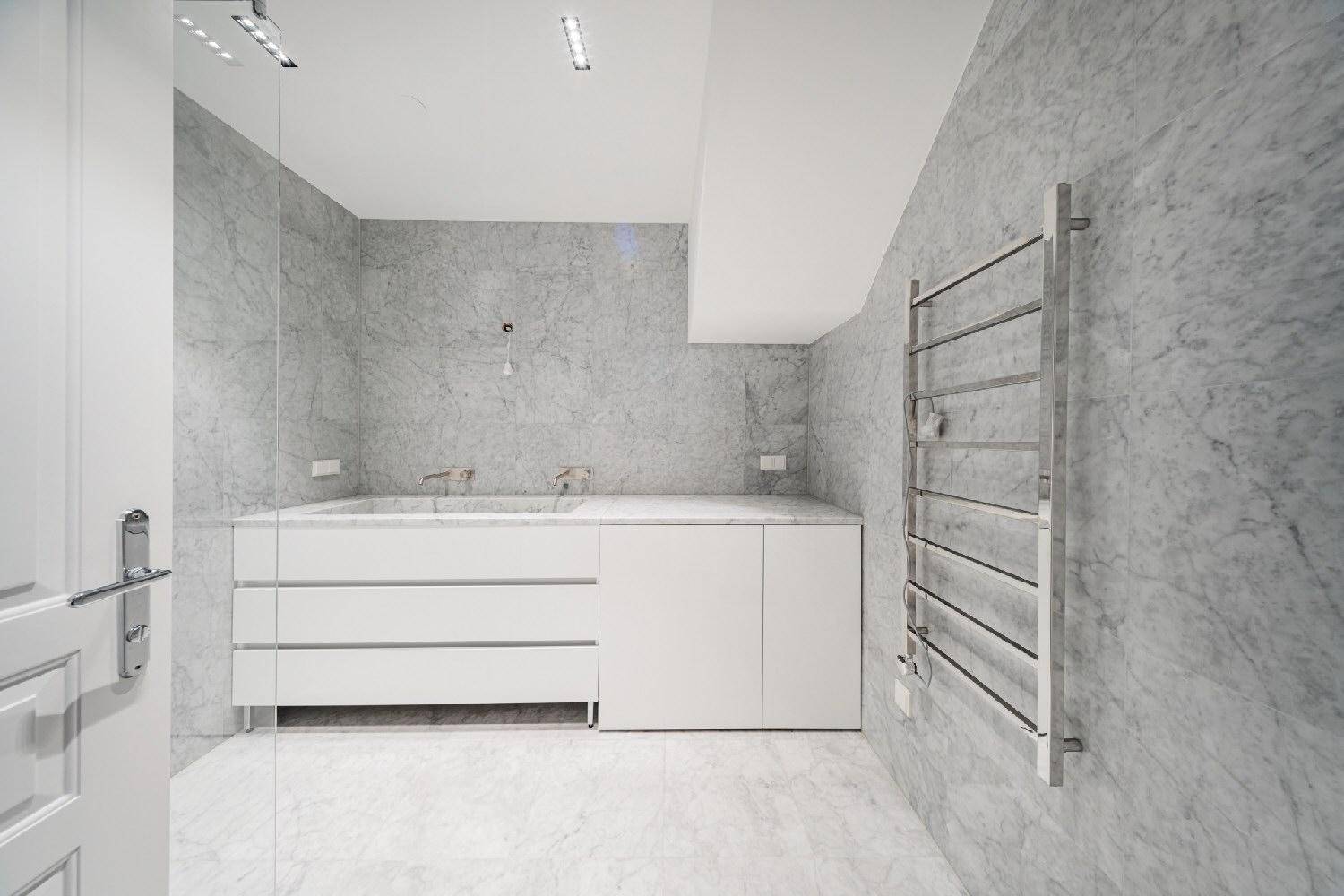 Elegantes Badezimmer mit Marmorfliesen, integriertem Waschtisch und beheiztem Handtuchhalter.
