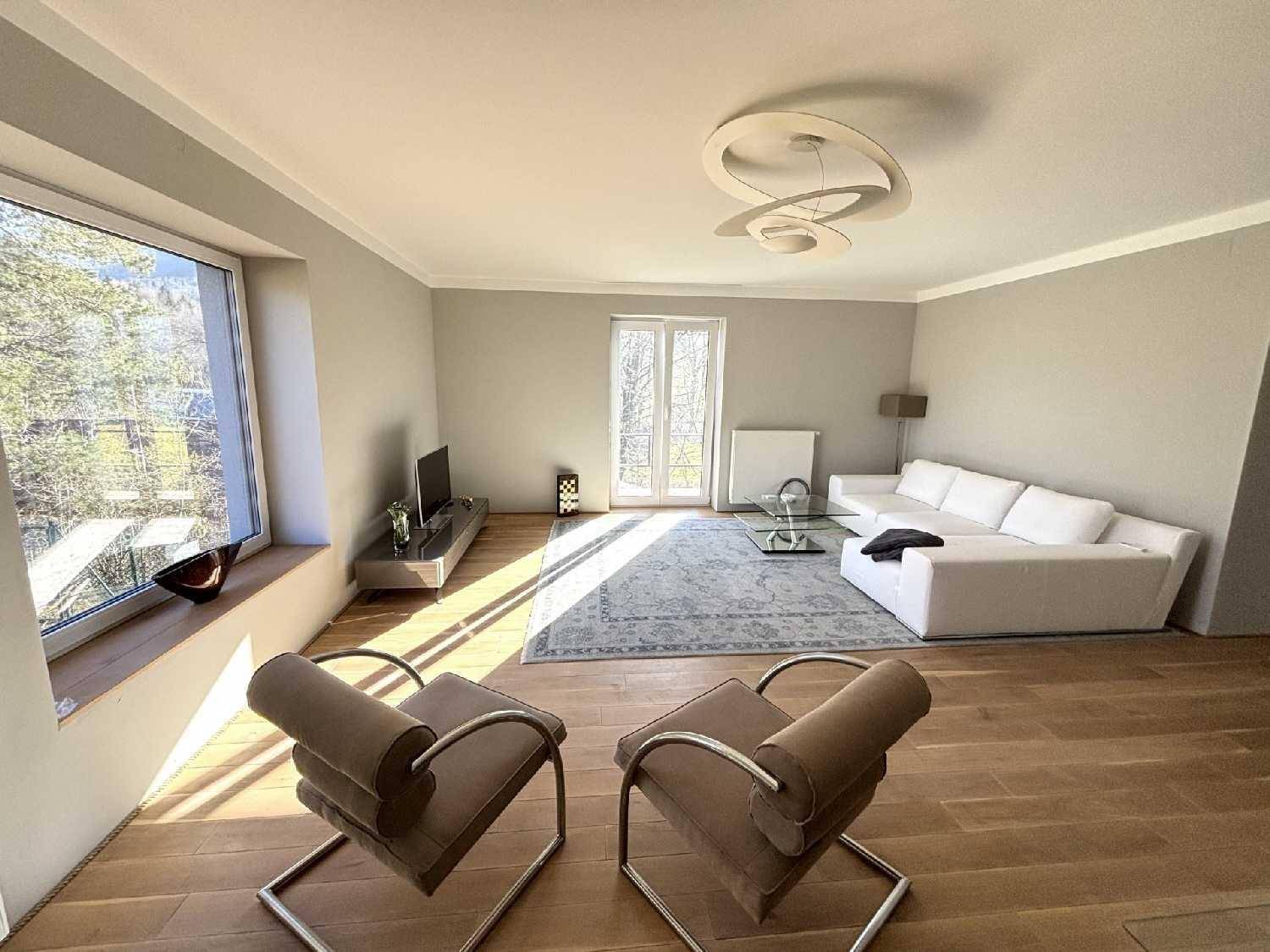 Modernes Wohnzimmer mit bequemen Sesseln, Holzboden und viel Tageslicht.