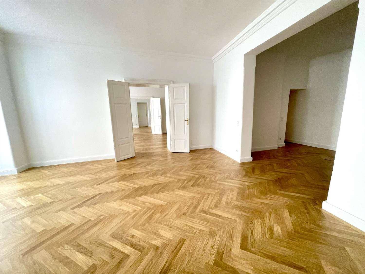 Geräumiger Wohnbereich mit elegantem Fischgrätparkett und hohen Decken, der durch offene Türen verbunden ist.