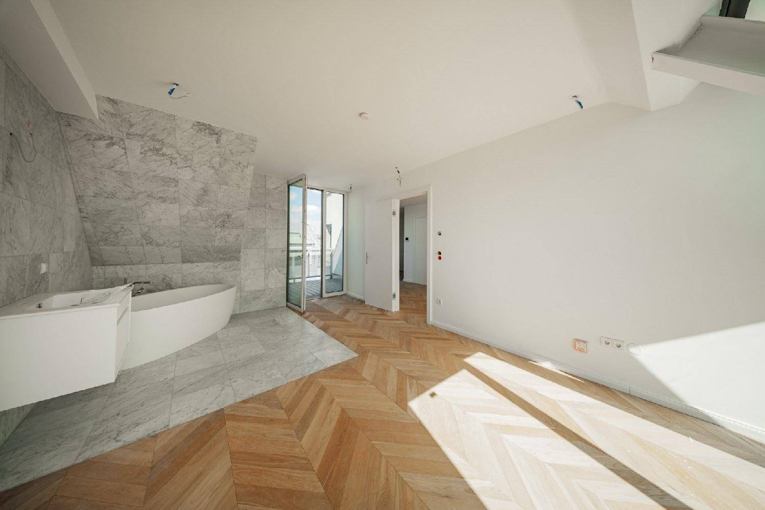 Elegantes Badezimmer mit freistehender Badewanne, Marmorwand und Zugang zu einem Außenbereich.